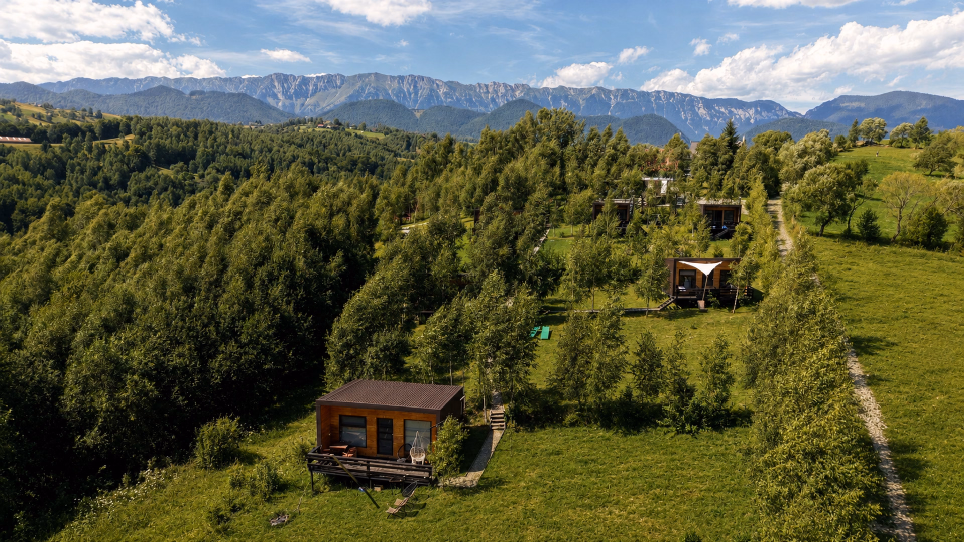 Cabane din lemn cu vedere către Piatra Craiului și Bucegi